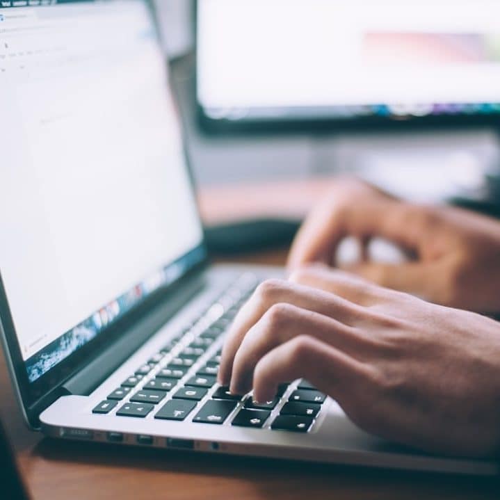 Zwei Hände tippen auf einem Laptop